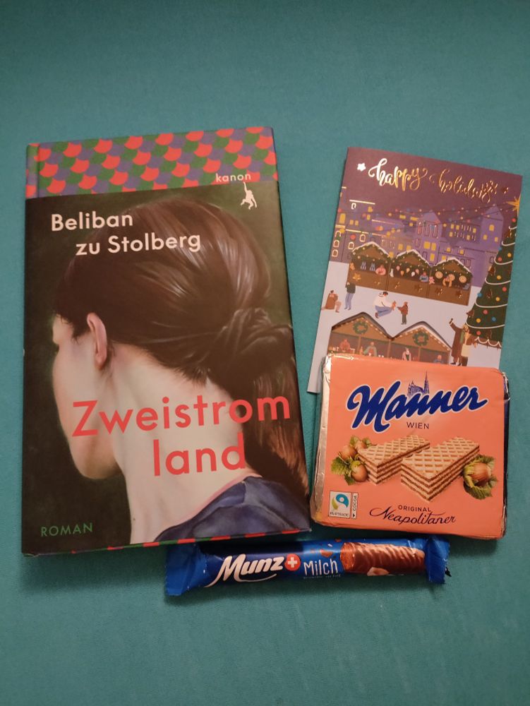 Buch mit Titel "Zweistromland", eine Grußkarte und Kekse und Schokolade 