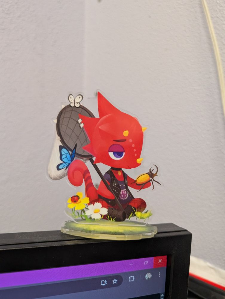 A standee of Flick, a red chameleon from Animal Crossing, holding a Hercules beetle and bug net. 