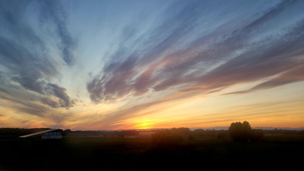 A Nice sunset in the countryside, with dark cirrus clouds in an orange sky.