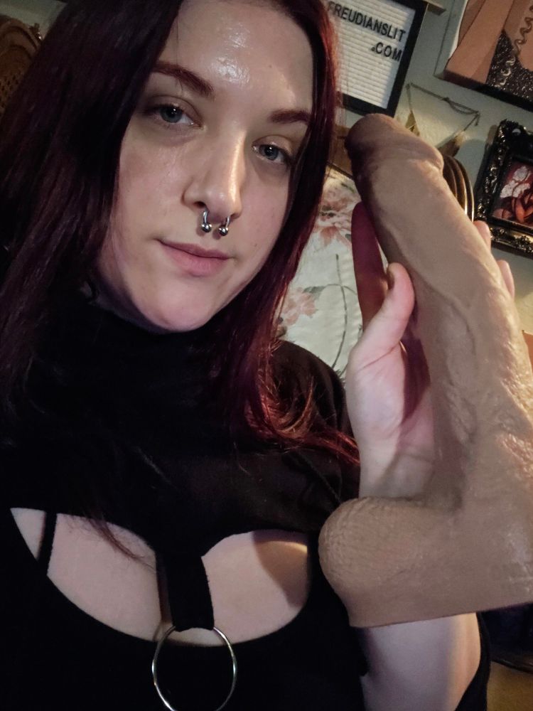 a redheaded woman holds up a very large phallus