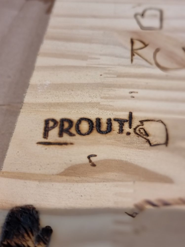 Le mot "Prout" pyrogravé sur du bois.