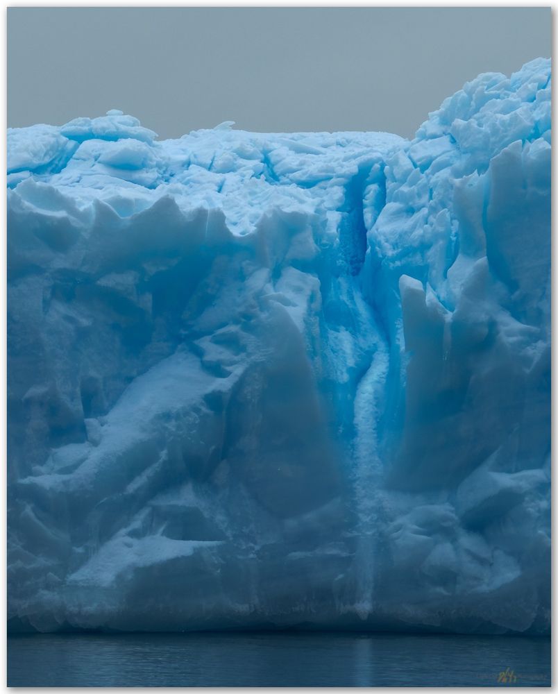 Close up of blue ice of an iceberg near the Antarctic Peninsula, taken from a zodiac on a cloudy, grey day. 