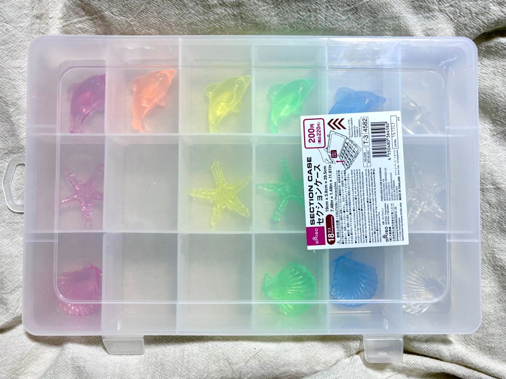 仕切りつきケースにプラスチック製の海産物型飾りを収めたもの。蓋を閉めた状態。