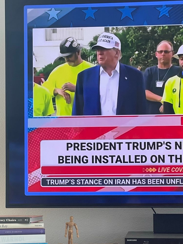 At White House flagpole ceremony, trump talks while construction worker standing behind him looks at this watch. 