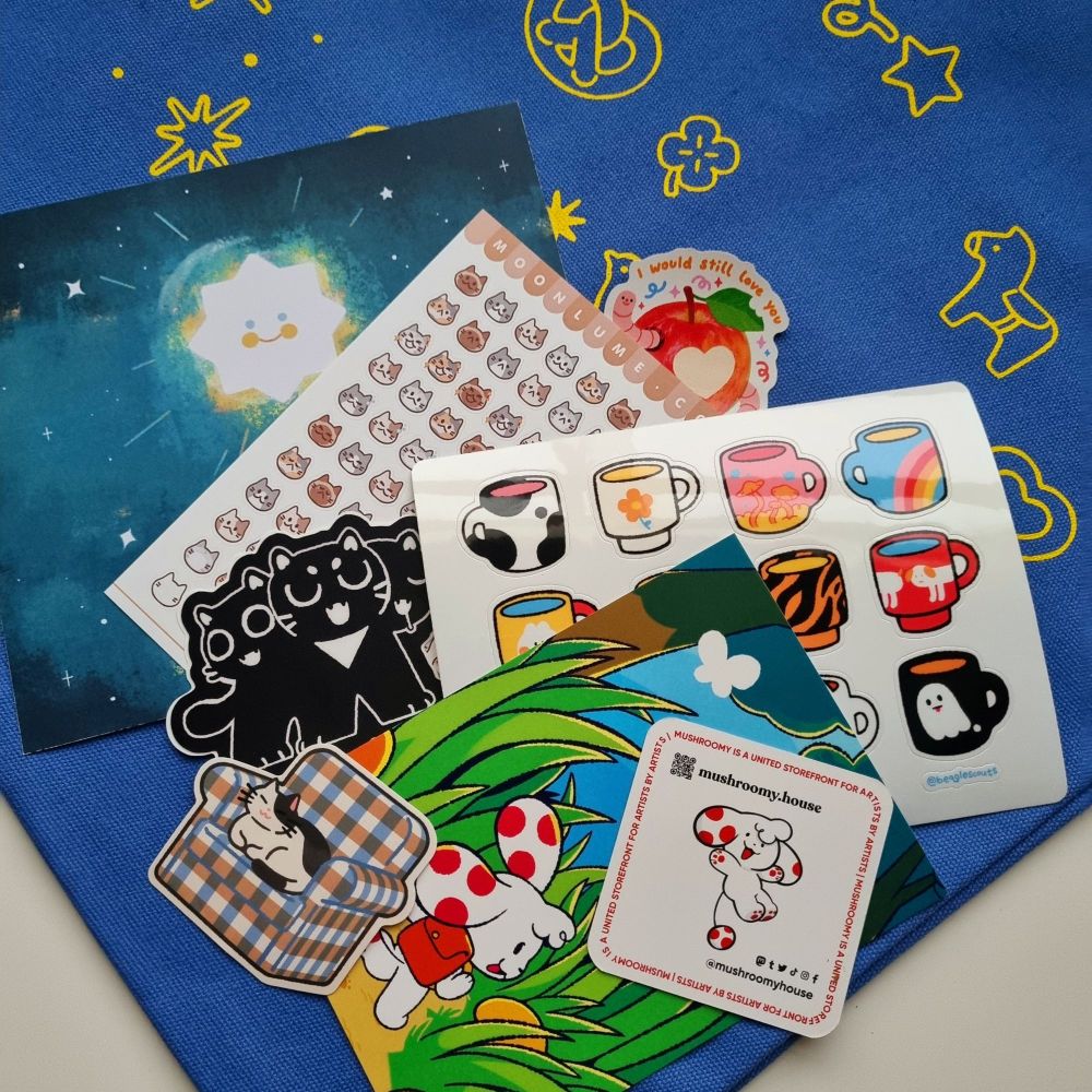 Scattered stickers and art prints over a tote bag, all purchased from Mushroomy.