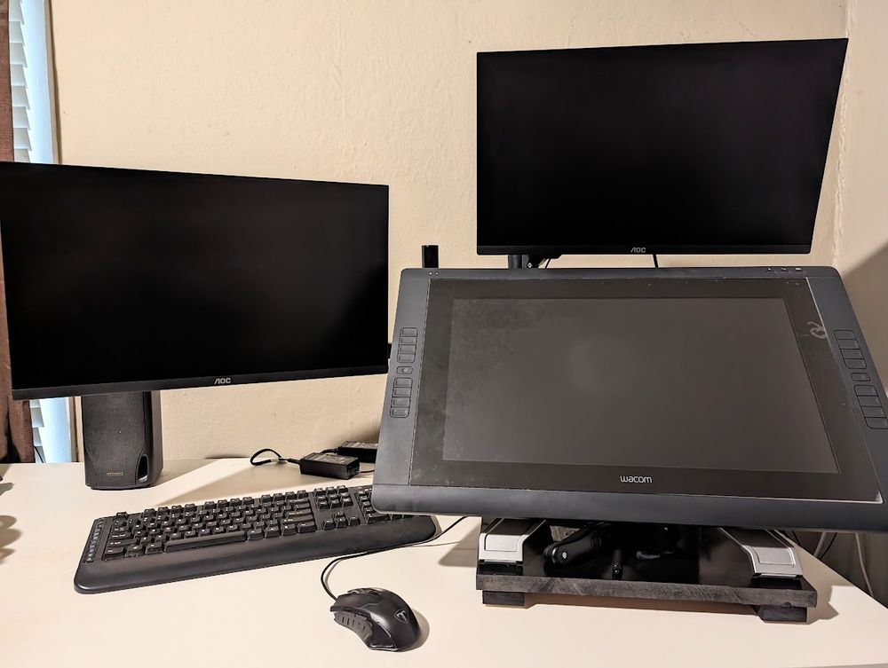 A photo of my desk showing 2 monitors, a wacom cintiq, and a mouse and keyboard.