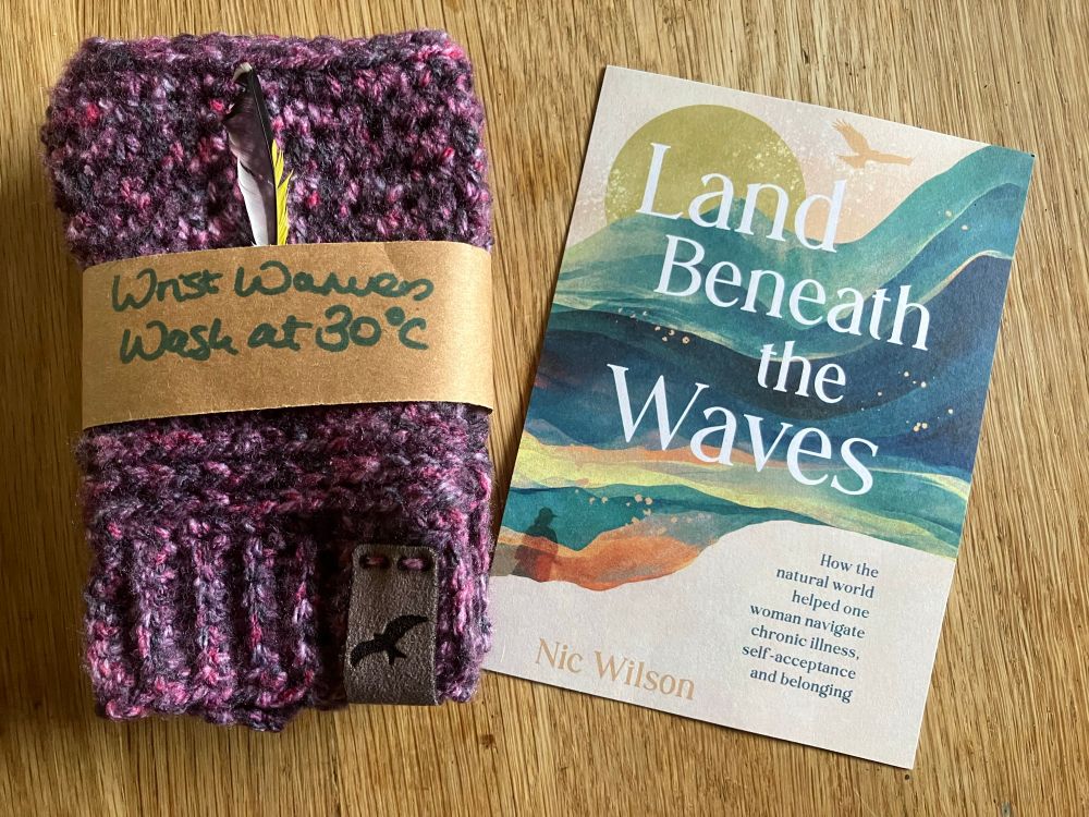 Beautifully handcrafted, crocheted,  heather-coloured wrist warmers, with a goldfinch feather tucked in, and a postcard of Nic’s fab book, Land Beneath the Waves 