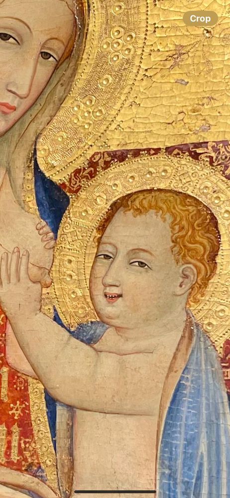 A thirteenth-century painting depicting a golden-haloed Baby Jesus smiling at the audience while holding the Virgin Mary's bare breast in both hands. The Virgin is serene. 

