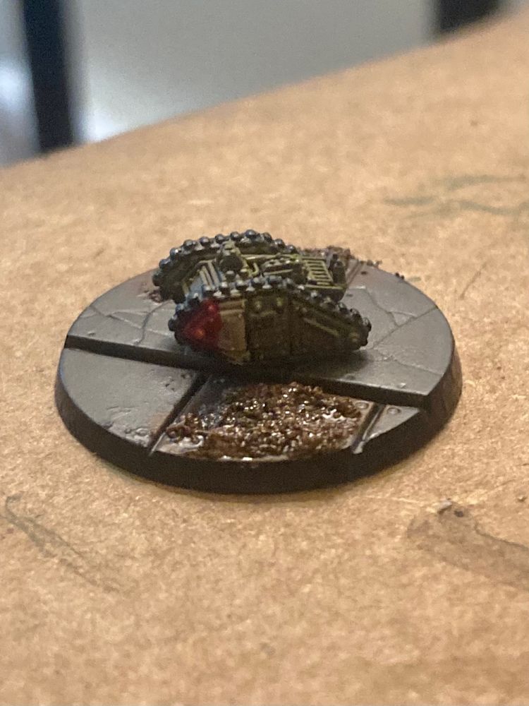 Very small 8mm scale legions imperialis small tank model, painted in green with a red and white marking on the front 