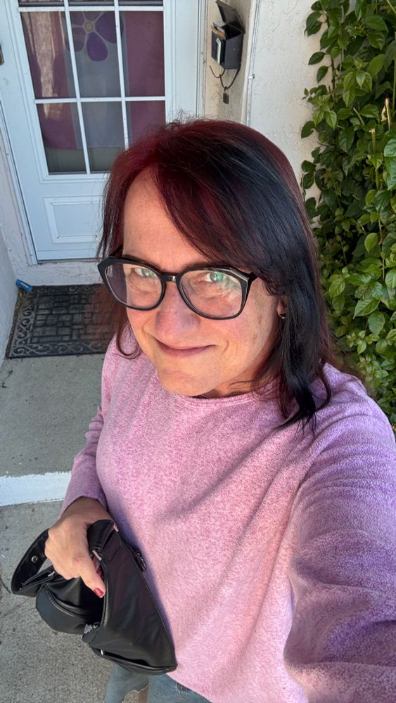 Mari in the sun in a pink sweatshirt and freshly colored hair