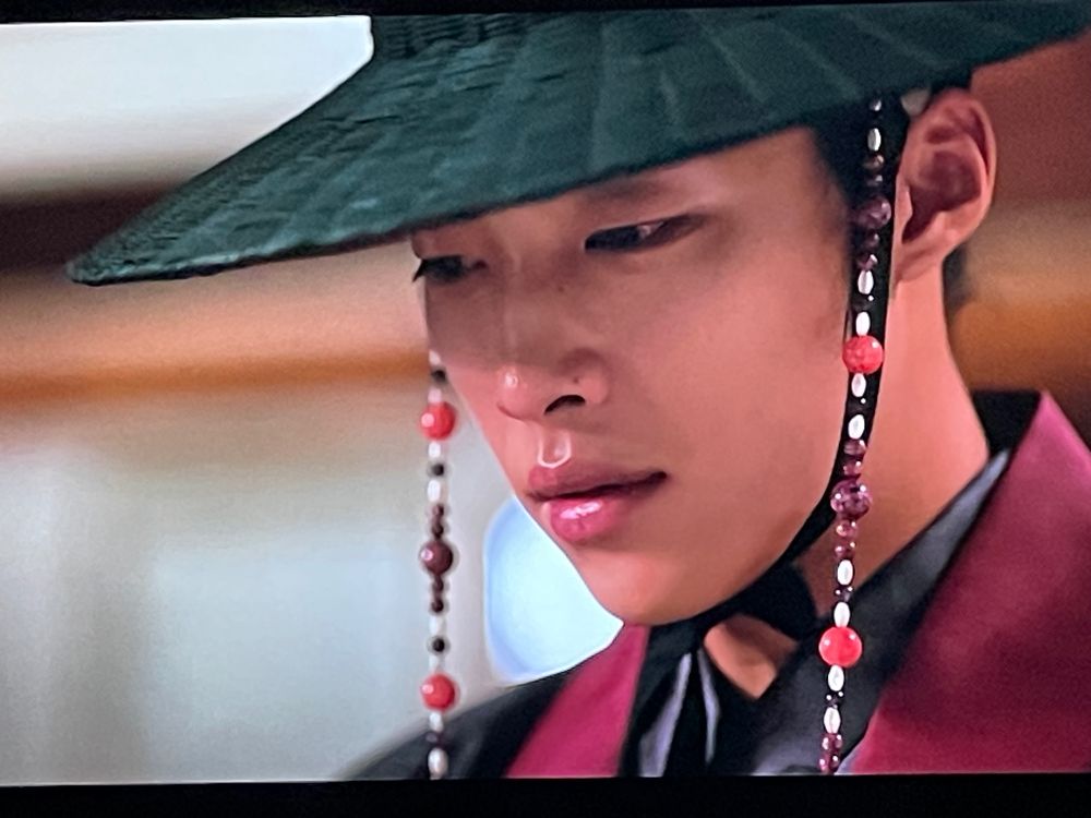 Nam Seonho in a black gat with red and white beads in episode 8 of My Country: The New Age.