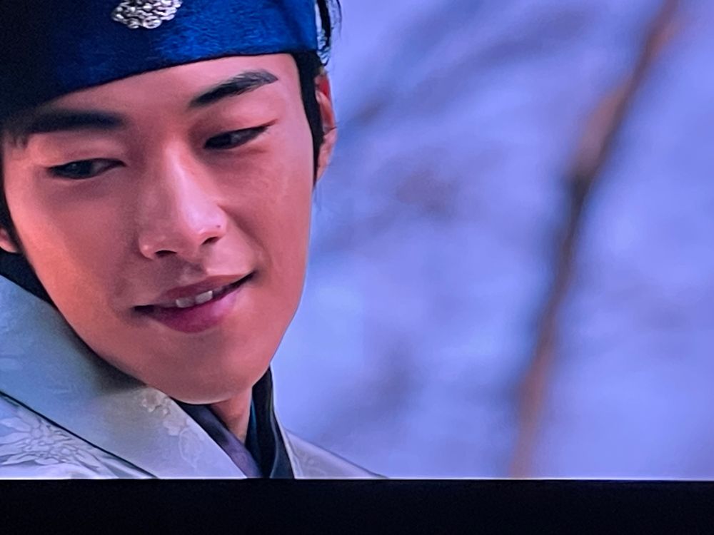 Nam Seon-ho smiles fondly down at Seo Hwi (offscreen) in episode 1 of My Country: The New Age. 