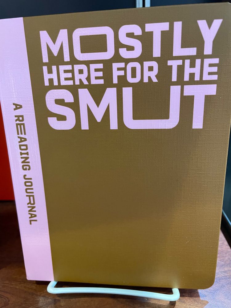 A brown and pink reading journal. Large pink text on the cover reads: MOSTLY HERE FOR THE SMUT.