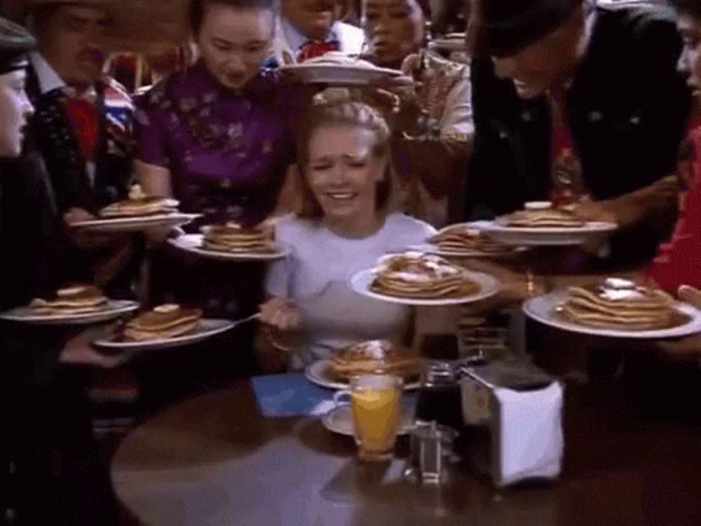 a woman sitting at a table with plates of pancakes on it .