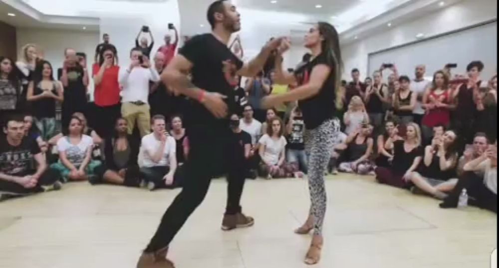 a man and a woman are dancing salsa in front of a crowd of people .