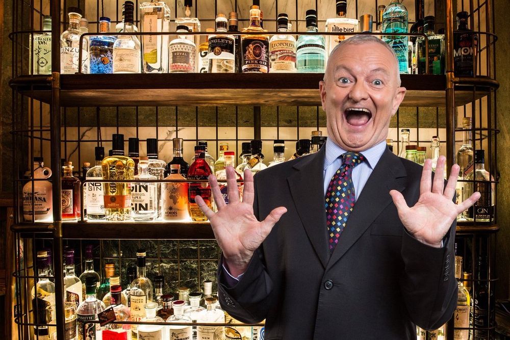 Very excited Antony Green in front of a wonderfully stocked liquor cabinet