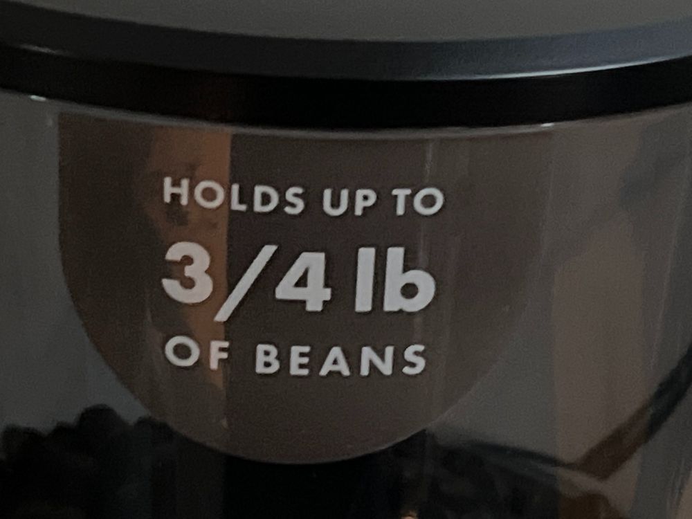 close-up of a sticker on a coffee grinder that says "holds up to 3/4 lb of beans"