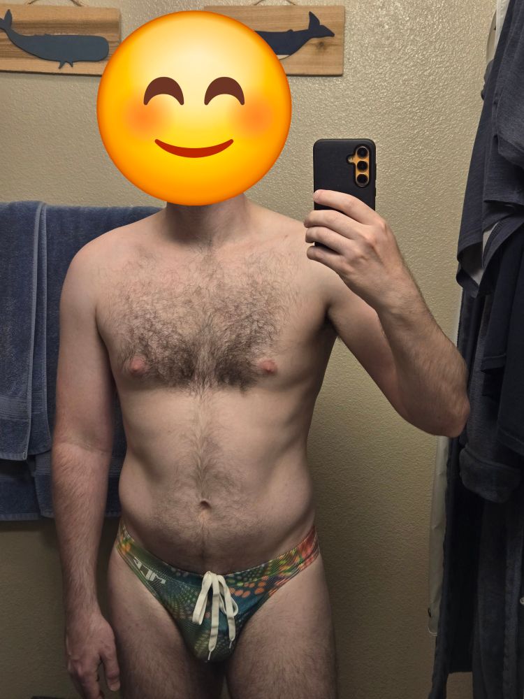 Man posing in front of a mirror in a speedo