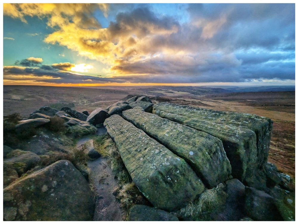 Colour photo of the KitKat stones on Higger Tor in the Derbyshire Peak District with the sunrise beyond.