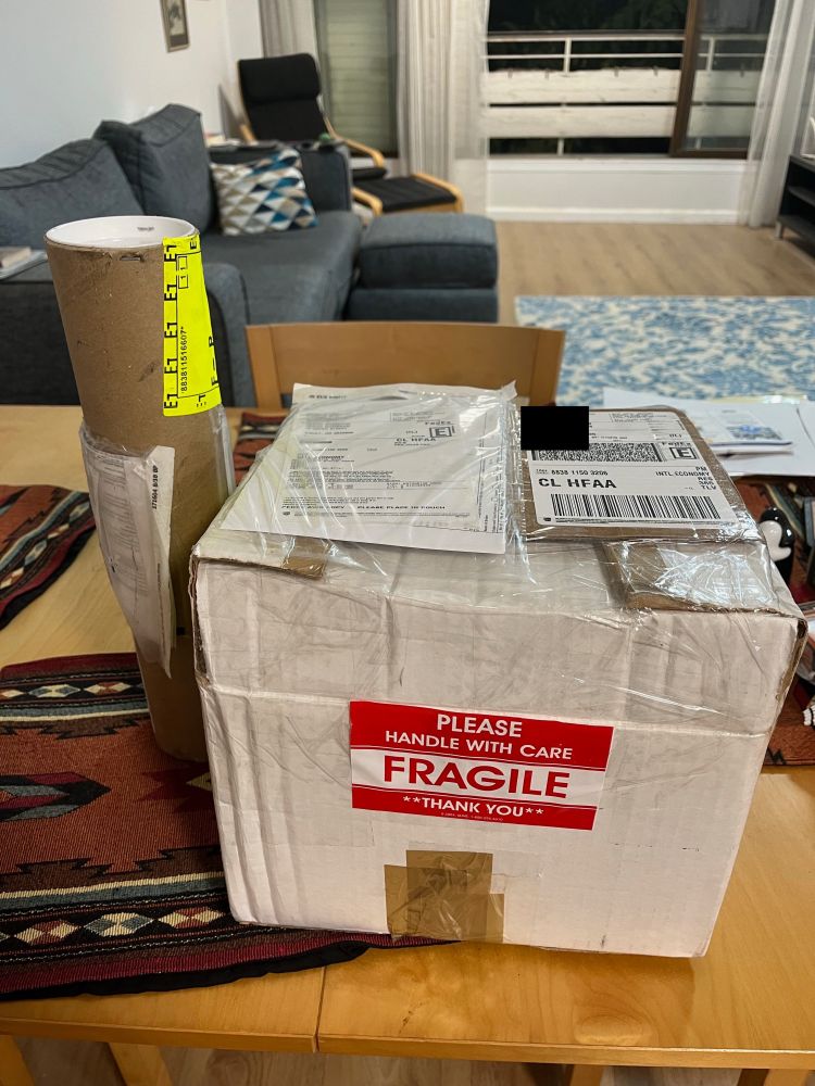 A large square package and a tall cylindrical packing container