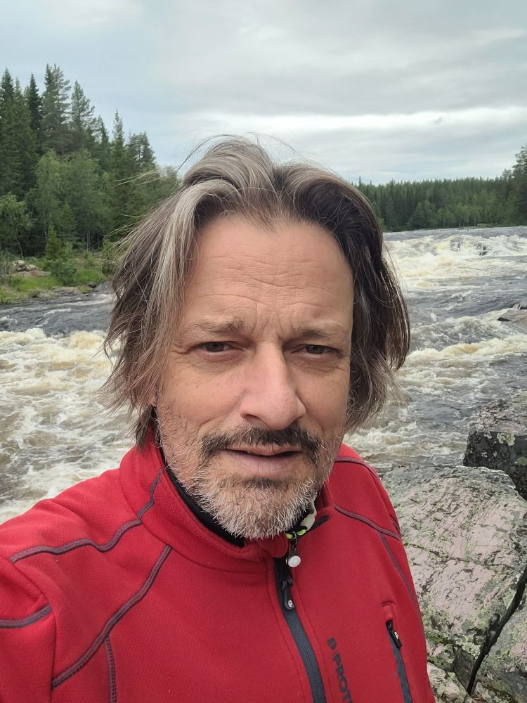 Oude man in rode fleece voor stroomversnelling in de Strorån rivier