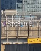 People on an overpass with letters that spell out: STOP ICE 