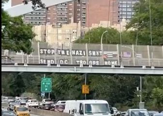 Letters on overpass spelling out: Stop the Nazi Sh*t Send DC Troops Home