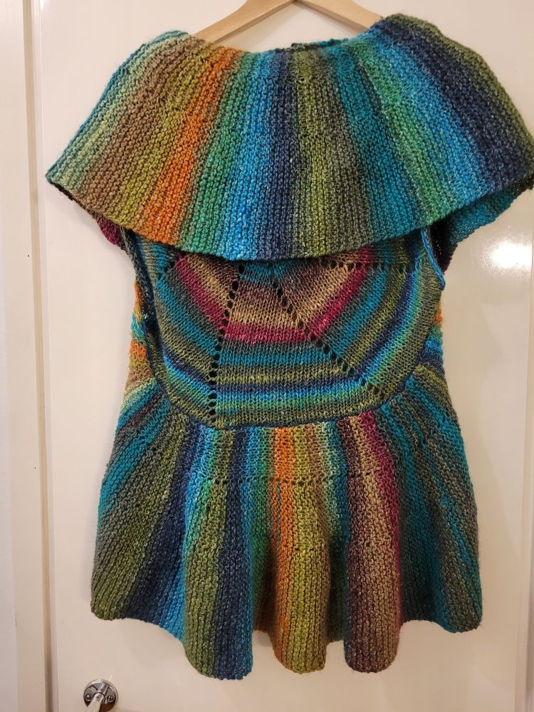 Liivi takaa kuvattuna, tässä näkyy hyvin sen rakenne eli keskiosa on neulottu ympyräksi, ja sitä kehystää leveä poikittain neulottu reunus