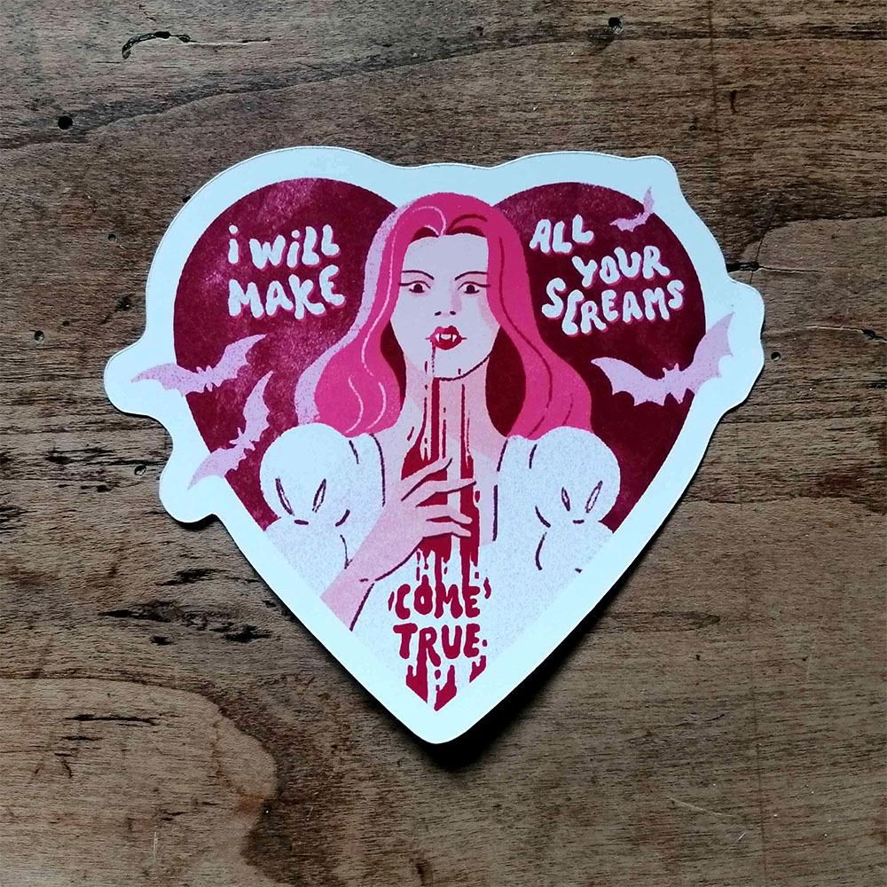 Photo of a heart shaped sticker featuring a pink haired vampire with blood dripping from her mouth with the text "I will make all your screams come true"