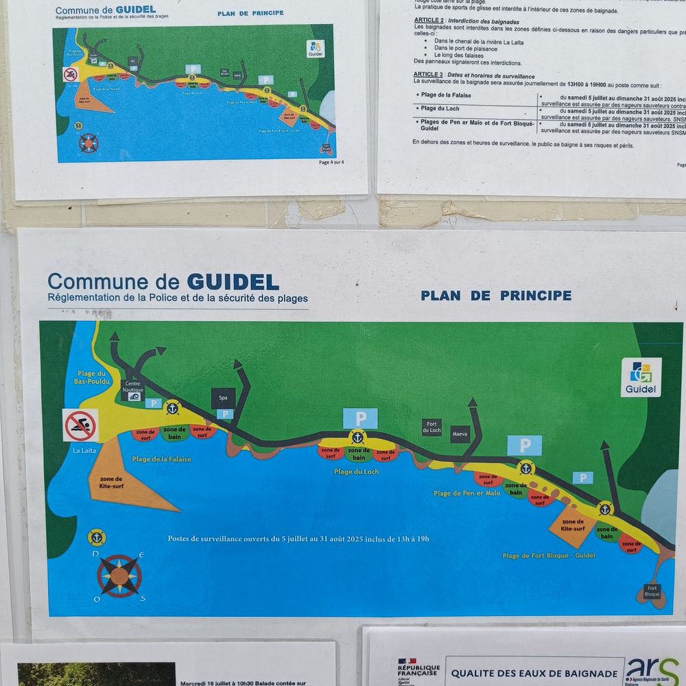 An einem Schild hängt eine Strandkarte mit Hinweisen auf die Bade-, Surf- und Kitesurfbereiche. Guidel, Frankreich.