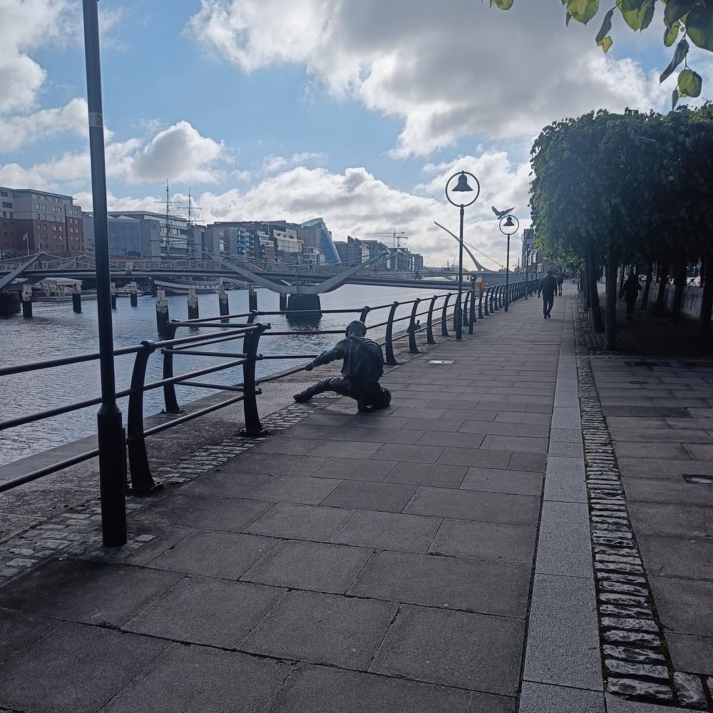 Das Liffey in Dublin. Im Vordergrund die Statue eines Mannes, der ein Schiff schleppt..