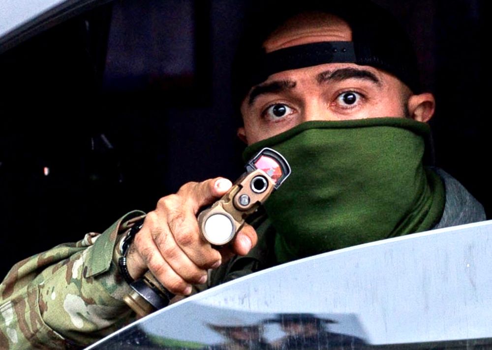 Close up of ICE goon pointing gun at the phone/camera.