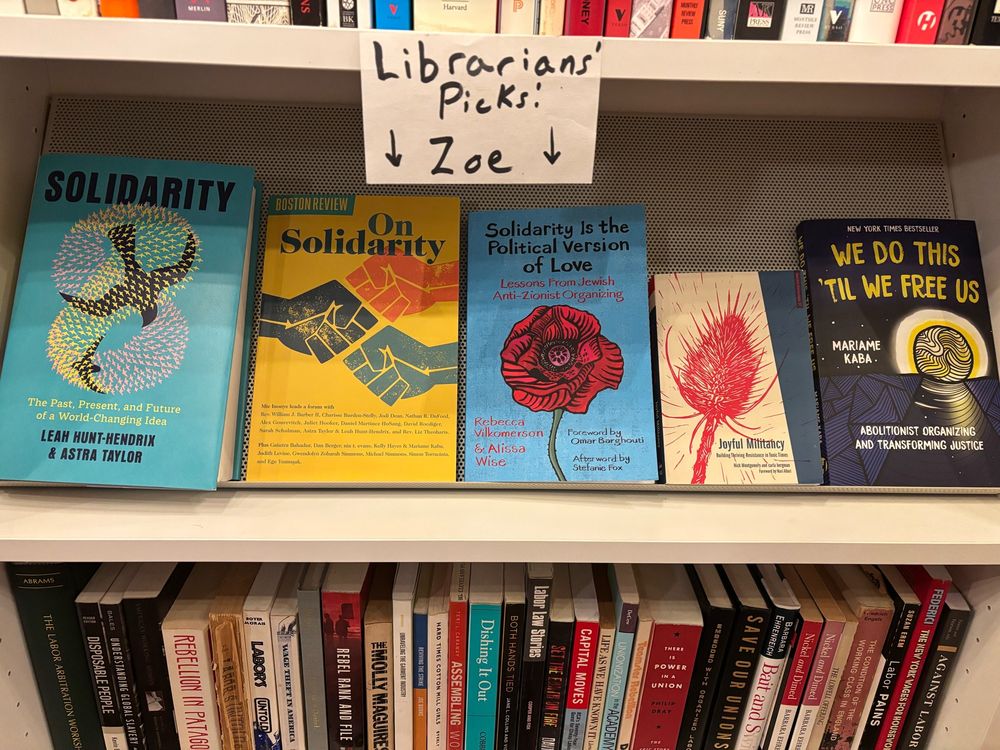 A shelf in a library labeled “Librarians Picks - Zoe.” The shelf has 5 books with their covers on display: 

“Solidarity: The Past, Present, and Future of a World Changing Ideas”

“On Solidarity”

“Solidarity Is the Political Version of Love: Lessons from Jewish Anti-Zionist Organizing”

“Joyful Militancy: Building Thriving Resistance in Toxic Times”

“We Do This Till We Free Us: Abolitionist Organizing and Transforming Justice”

Above and below this shelf you can see spines of books on political economy (above) and labor (below).
