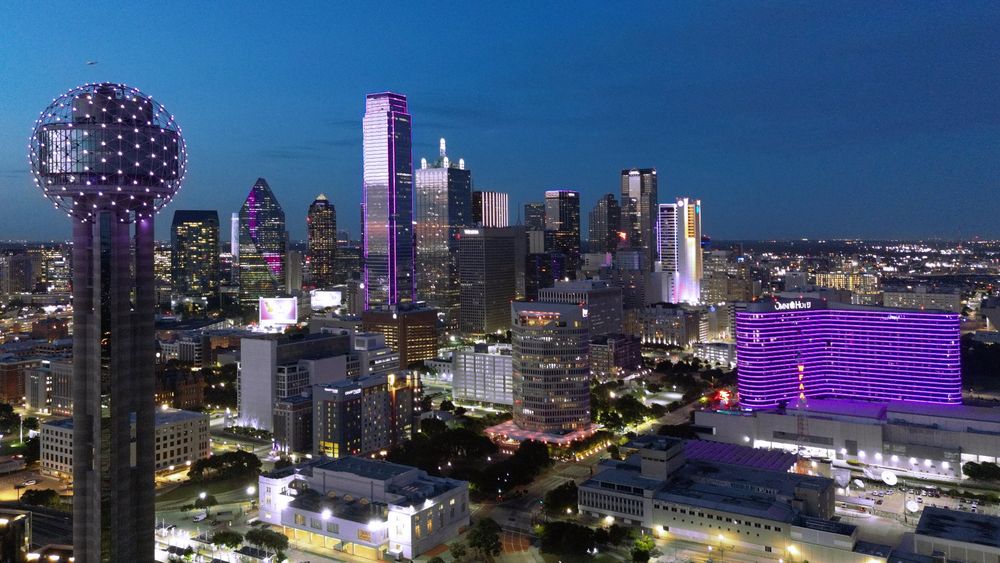 The Dallas skyline with several buildings lit in purple light. One looks like an ARMY bomb (almost)