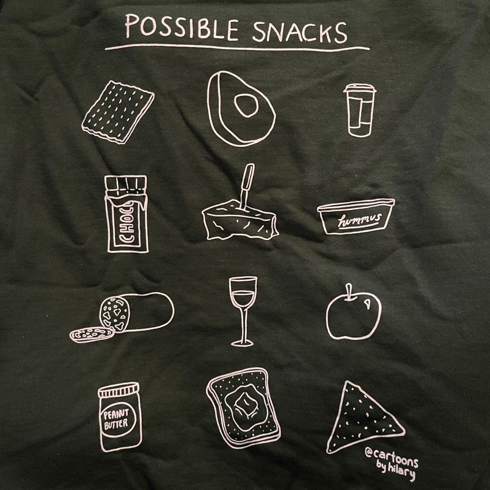 A sweatshirt that says “possible snacks” with pictures of snack foods like apples, peanut butter, hummus, cheese, etc