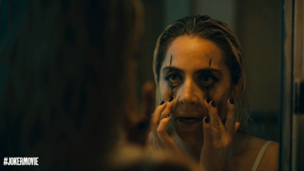 a woman is looking at her face in a mirror with the hashtag #jokermovie