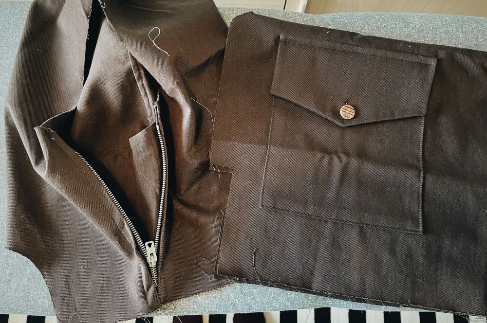 Vaiheessa oleva anorakki, jossa valmiina tasku ja vetoketju 