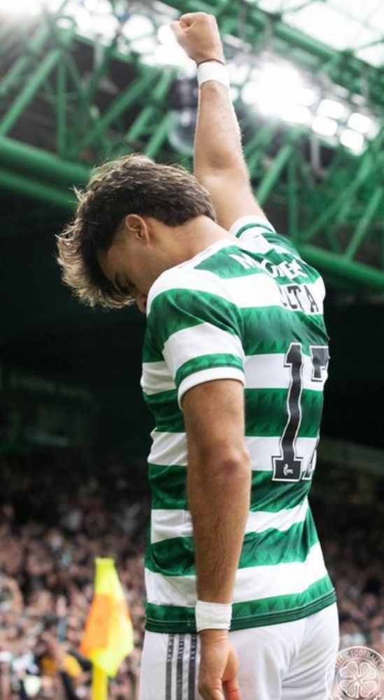Celtic player Jota stands one arm raised celebrating scoring a goal.