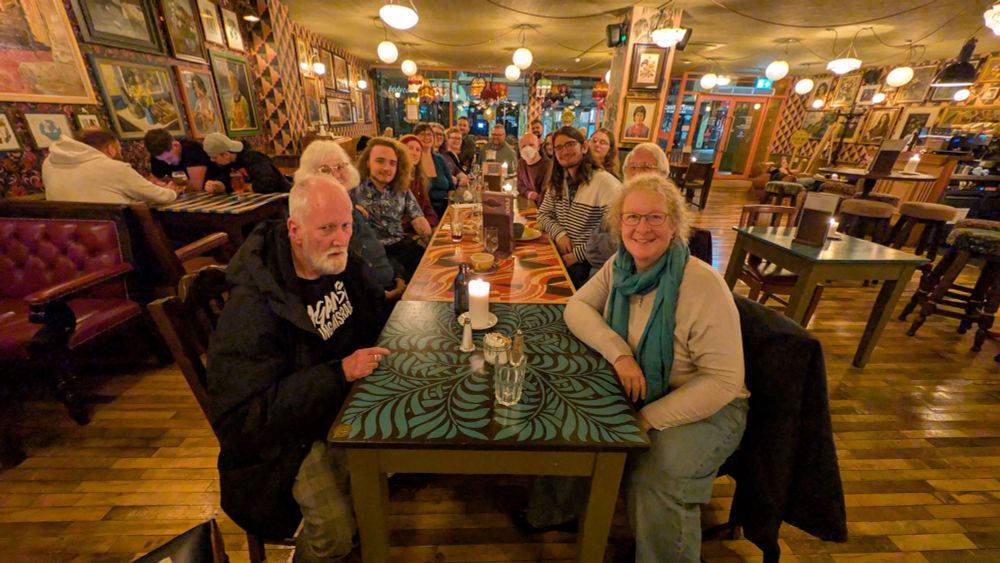 Long table with many Green Party people sat at it looking at the camera smiling 