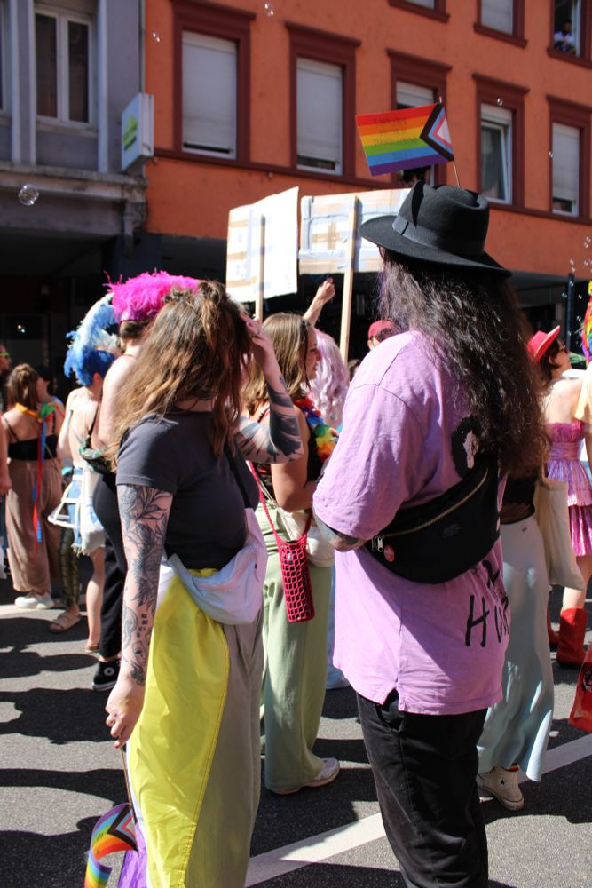 Photo taken during Christophers Street Day in my Town in Germany on June 11th 2023. Surrounded by many LGBTQ+ People this Picture focuses on Two people mostly representing the Colours of the Nonbinary: Yellow, White, Purple & Black