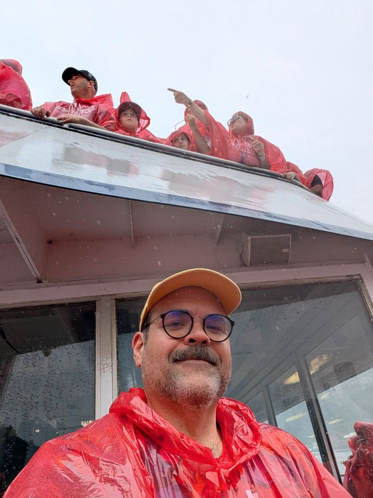 A picture of me, resplendent in red plastic, looking damp. In the background, a fellow tourist points dramatically towards what I can only assume is the future. 