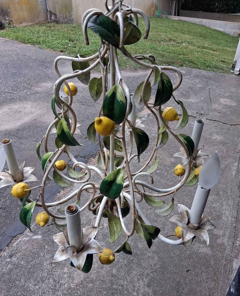 A mid-century tole chandelier painted white with green leaves and yellow lemons. 