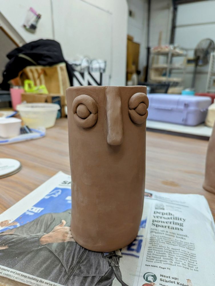 Tall vase made of clay with eyes and a nose