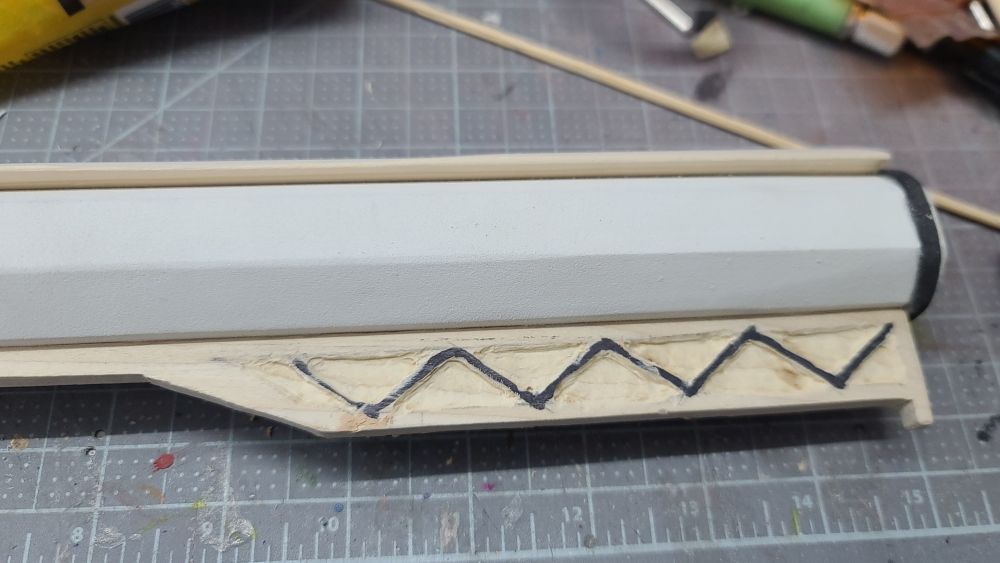 A closeup of the sight on the end of a prop rifle. It has a zigzag detail drawn on it with the negative space around it carved out.