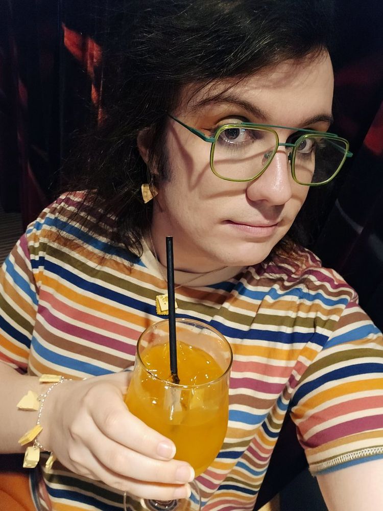 Same banger outfit but now they have a bright orange sparkly drink of dubious alcoholic percentage.