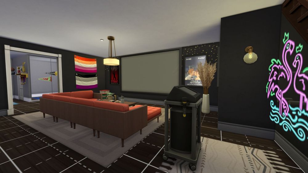 screenshot from the sims four of a basement with a huge tv and sitting area, karaoke machine, and lots of decor on the walls. you can also see further back into a home gym just beyond an arch way