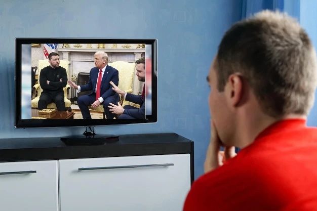 Homme consterné devant sa TV et regardant la rencontre Zelensky-Trump