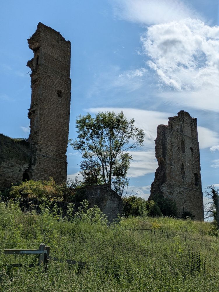 Two ruined towers of the castle at Sheriff Hutton framing a tree on a sunny day
