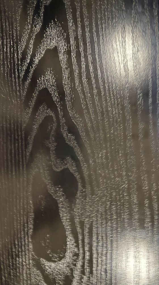 "Close-up of the natural wood grain pattern on a dark wooden surface, with visible highlights reflecting light. There are no cards on the desk."