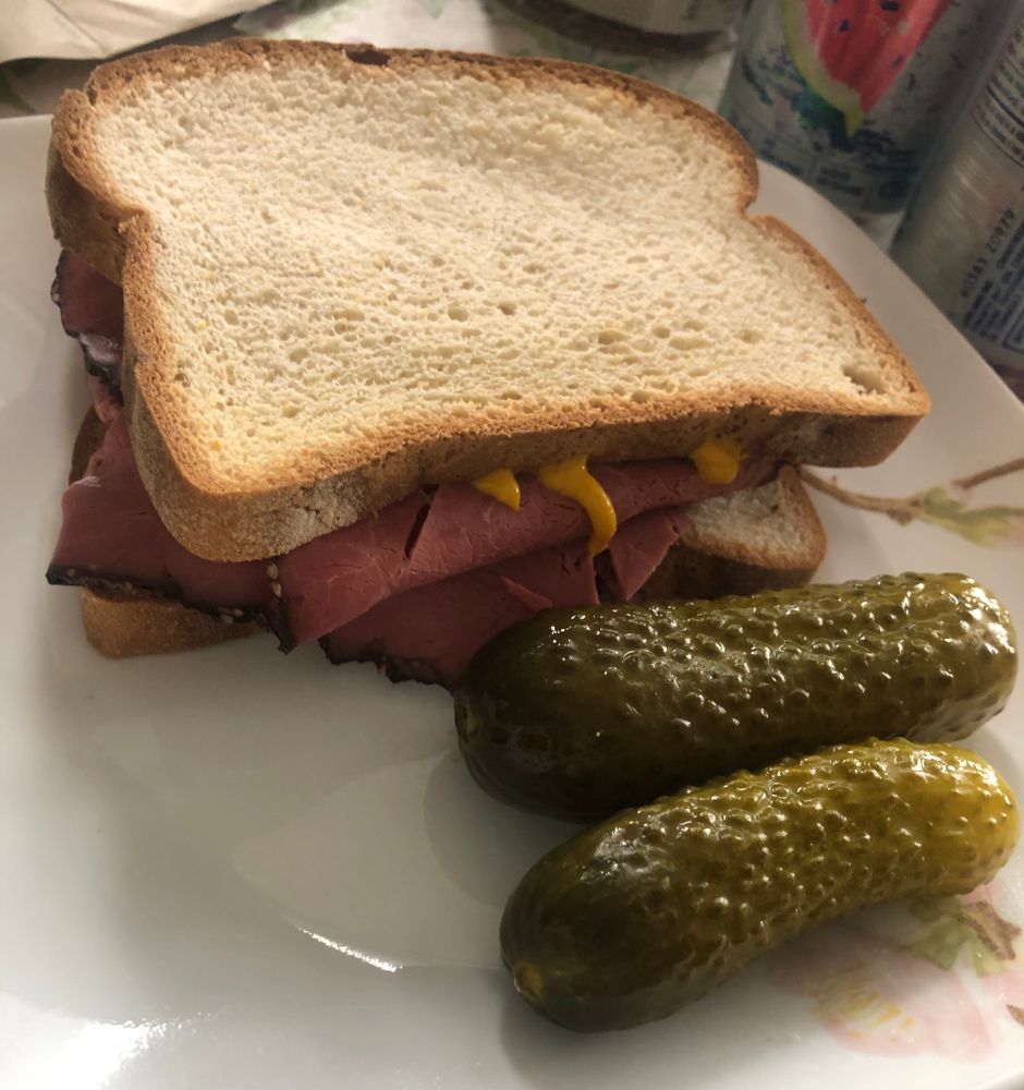 A Montreal smoked meat sandwich and two dill pickels 